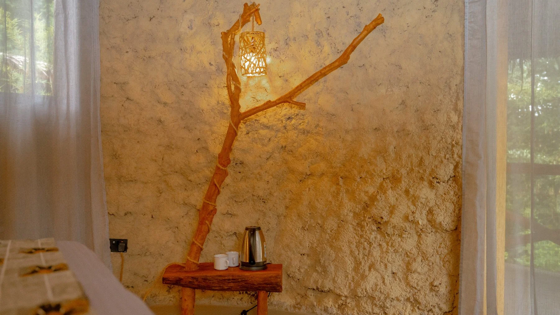 A branch-form lamp beside the bed in a guest room at Sio Maasai
